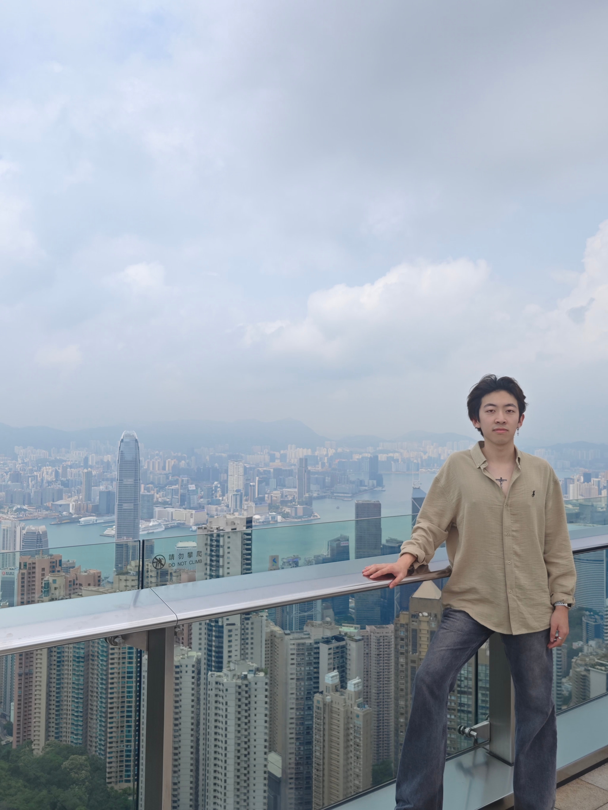 Linfeng Fan standing at an elevated overlook with a city skyline behind him.
