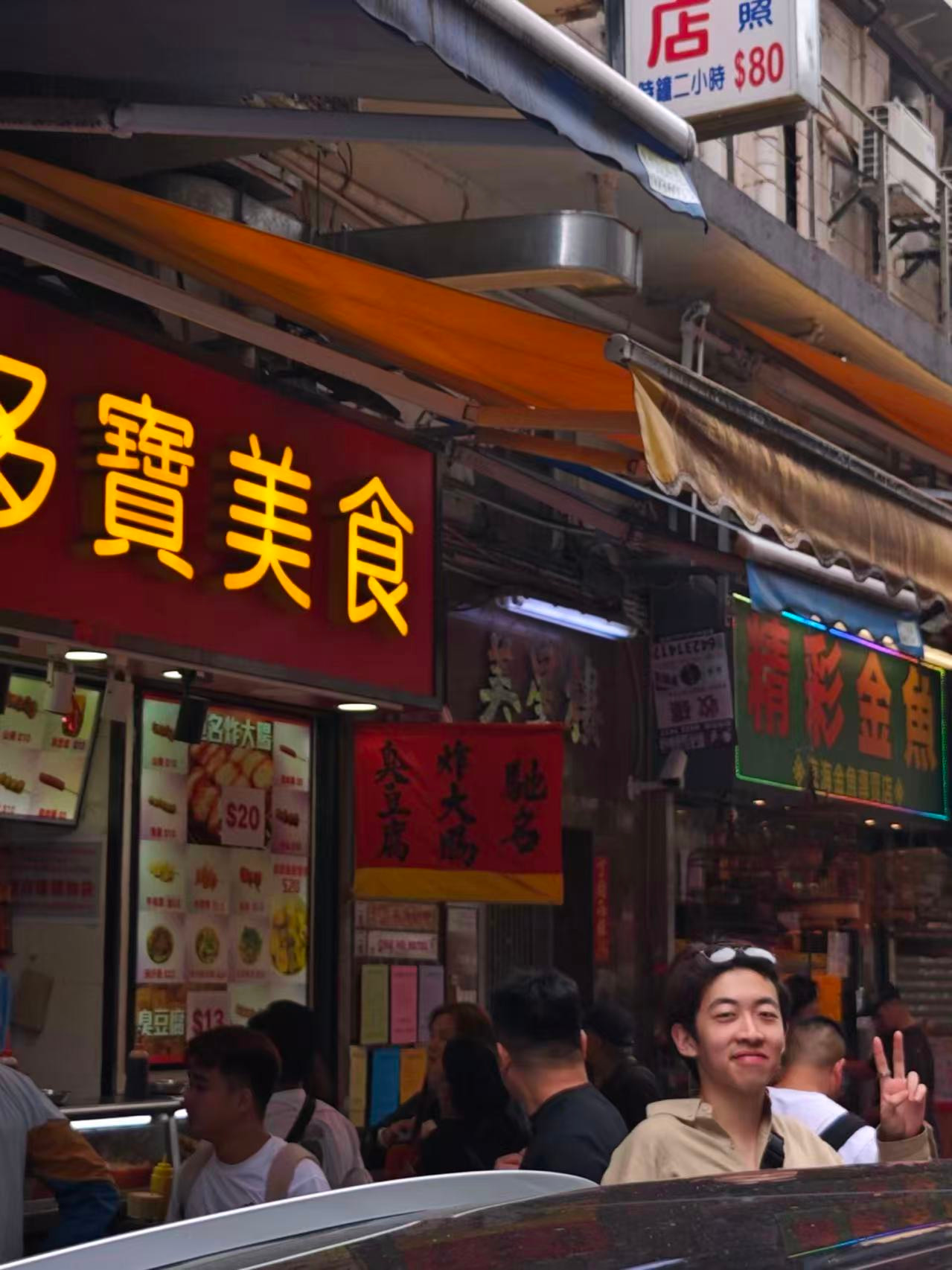 Linfeng Fan making a peace sign on a busy street.